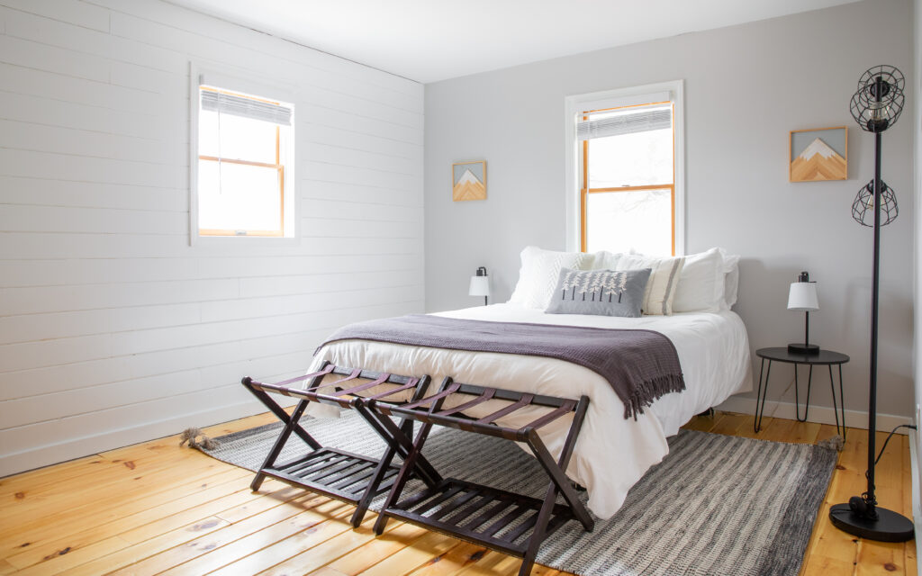 light and airy bedroom with light blue walls, wood floor and grey accents
