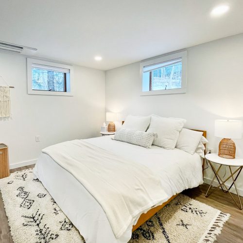 neutral bedroom with king bed, white sheets and wood accents